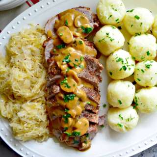 Polish Feast: Roasted Pork, Potato Dumplings, Sauerkraut, and Red Cabbage