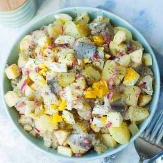 Herring salad with potatoes, eggs, cucumbers in brine and apples