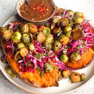 Sweet potato with cabbage kale salad, roasted Brussels sprouts and tahini sauce