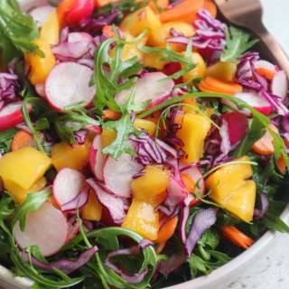 Liver rescue salad with arugula, mango, radishes, red cabbage and orange dressing